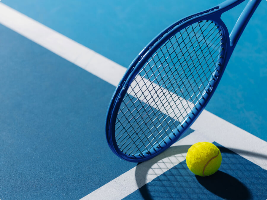 Raqueta de tenis y pelota en una cancha, proyectando sombra