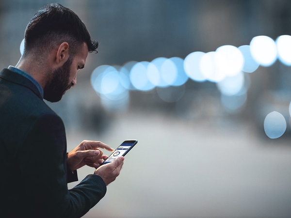 En un ambiente al aire libre, ejecutivo mirando la pantalla del celular usando la app de BTG Pactual
