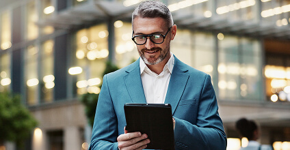 Ejecutivo sosteniendo una tablet, mirando y sonriendo a la pantalla