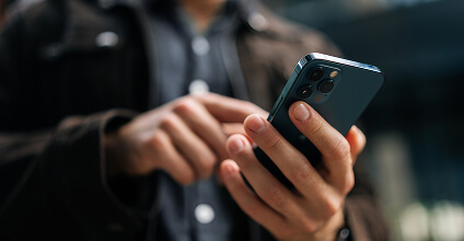 Manos de un hombre sosteniendo el celular y navegando en la app de BTG Pactual