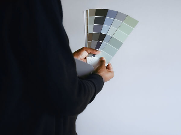 Persona de espaldas en segundo plano, con foco en una paleta de colores para pintura de ambientes